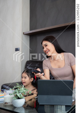 Mother and daughter watching tv together on couch. Lifestyle family moment Mother and daughter watching tv together on couch. Lifestyle family moment 112995202