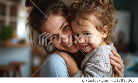 Affectionate loving middle aged mother cuddling child. Excited to see daughter, happy senior older mom cuddling her, sitting together on comfortable sofa in living room 112995363