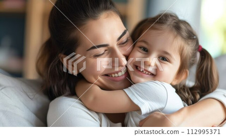 Affectionate loving middle aged mother cuddling child. Excited to see daughter, happy senior older mom cuddling her, sitting together on comfortable sofa in living room 112995371