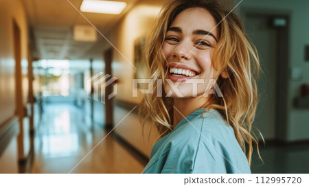Female Doctor Wearing Scrubs In Hospital Corridor 112995720