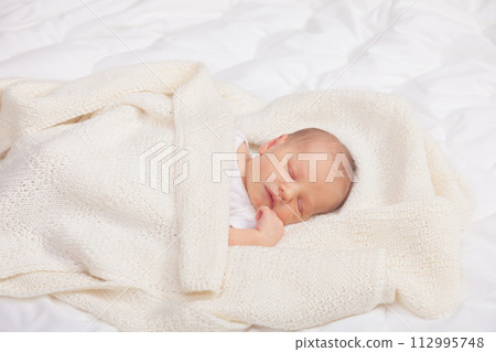 Newborn Baby Asleep Wrapped in Knit Blanket 112995748