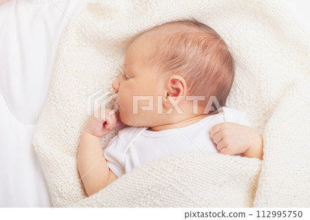 Newborn Baby Asleep Wrapped in Knit Blanket 112995750