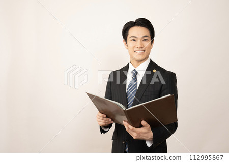 拿著文件的一位微笑的男性律師 拿著文件的一位微笑的男性律師 112995867