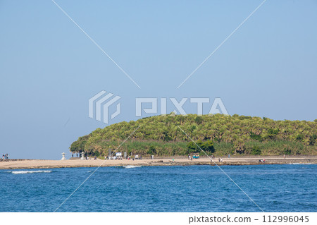 A god is enshrined on an island where shells have accumulated on a raised seabed under the blue sky, and around it are devil's washboards and eroded wavy rocks. 112996045