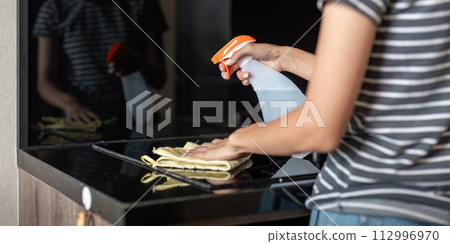Asian woman cleaning the table surface with towel and spray detergent 112996970