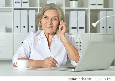 Senior business woman working in office with laptop Senior business woman working in office with laptop 112997160