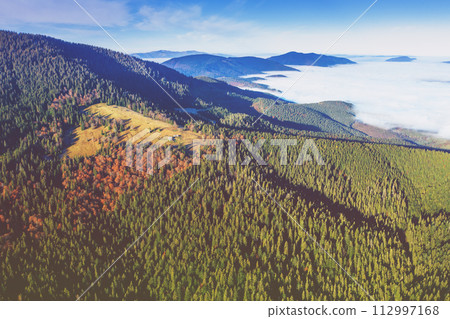 Aerial view of mountains above the clouds in the misty morning. View of the mountains in autumn. Beautiful nature landscape. Carpathian mountains. Ukraine 112997168