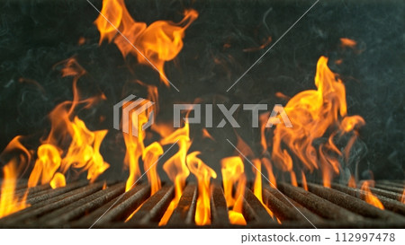 Close-up of cast-iron grate with fire flames, dark background Close-up of cast-iron grate with fire flames, dark background 112997478