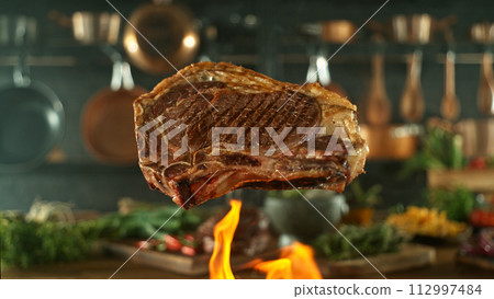 Close-up of tasty beef steak flying above cast-iron grate with fire flames 112997484