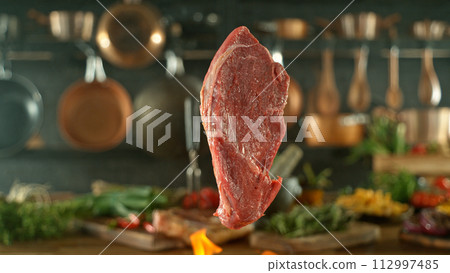 Close-up of tasty beef steak flying above cast-iron grate with fire flames 112997485