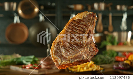 Close-up of tasty beef steak flying above cast-iron grate with fire flames 112997486