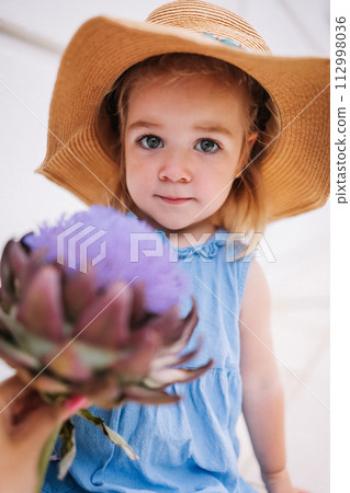 Cute little girl holding big artichoke flower in hands 112998036