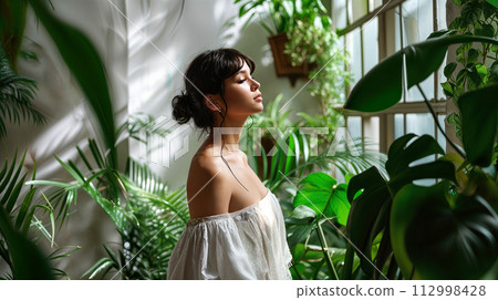 woman in a room with tropical green plants 112998428