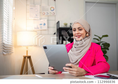 Young Muslim business woman hijab happy using digital tablet in modern office 112998836