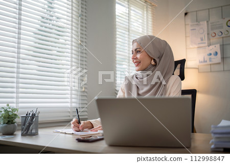 Asian Muslim businesswoman in hijab head scarf working with paper document in the modern office. diversity and office concept Asian Muslim businesswoman in hijab head scarf working with paper document in the modern office. diversity and office concept 112998847