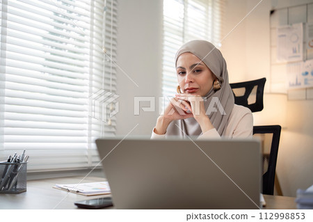 Asian Muslim businesswoman in hijab head scarf working with paper document in the modern office. diversity and office concept 112998853