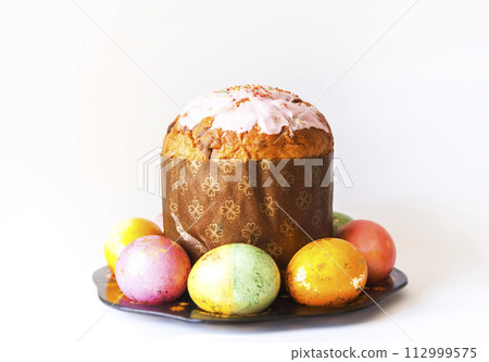 Colored eggs and sweet pastry. Traditional Easter food and decoration. 112999575