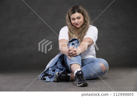 Beautiful fat woman in denim clothes on a gray background. Plus size model girl. Beautiful fat woman in denim clothes on a gray background. Plus size model girl. 112999805