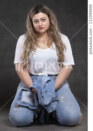 Beautiful fat woman in denim clothes on a gray background. Plus size model girl. 112999806
