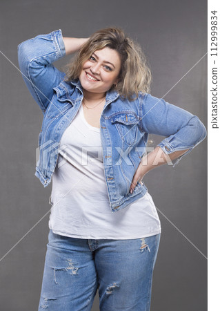 Beautiful fat woman in a denim suit on a gray background. Beautiful fat woman in a denim suit on a gray background. 112999834