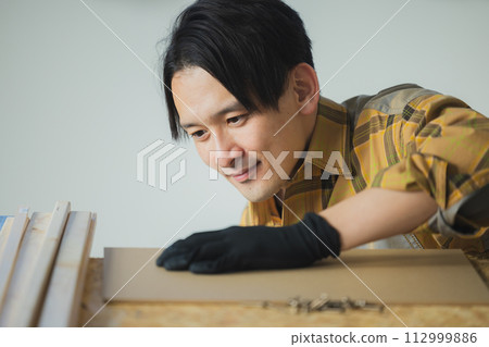 一個年輕人用電動螺絲起子工作 112999886