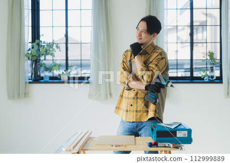 一個年輕人用電動螺絲起子工作 112999889