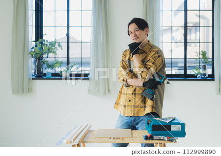 A young man working with an electric screwdriver A young man working with an electric screwdriver 112999890