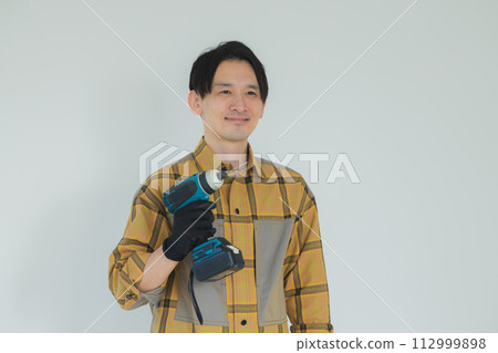 A young man working with an electric screwdriver A young man working with an electric screwdriver 112999898