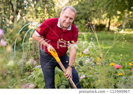 Portrait of an mature man with shovel in backyard of country house Portrait of an mature man with shovel in backyard of country house 112999967