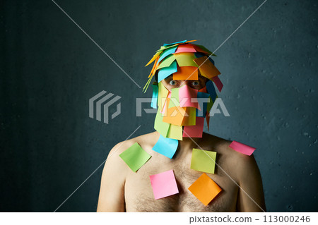 Shocked amazed man with colorful sticky notes all over his face and body 113000246
