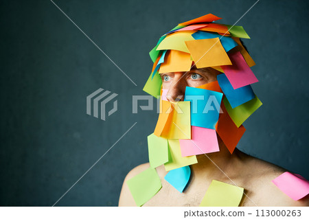 Close up portrait of man covered with colorful sticky notes all over his face and body over gray background Close up portrait of man covered with colorful sticky notes all over his face and body over gray background 113000263