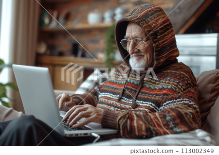 Happiness at work: elderly man in hood on sofa, devotedly doing business at computer 113002349