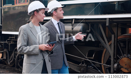 Young caucasian engineer man and woman in suit checking train with tablet in station, team engineer inspect system transport, technician examining infrastructure, transportation and industry. Young caucasian engineer man and woman in suit checking train with tablet in station, team engineer inspect system transport, technician examining infrastructure, transportation and industry. 113002873