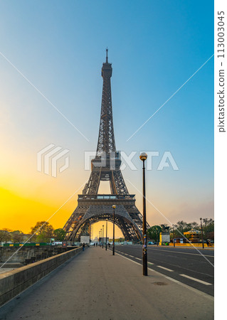 The Eiffel Tower is lit up at sunset. The sky is blue and the sun is setting, Paris, France The Eiffel Tower is lit up at sunset. The sky is blue and the sun is setting, Paris, France 113003045