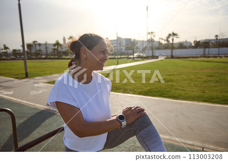 Female athlete resting after workout on sportsground, smiling looking aside. Sport Fitness Active Healthy lifestyle Female athlete resting after workout on sportsground, smiling looking aside. Sport Fitness Active Healthy lifestyle 113003208