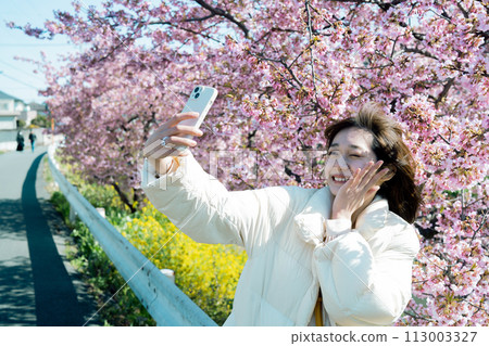 一位女士用智慧型手機與櫻花自拍 113003327