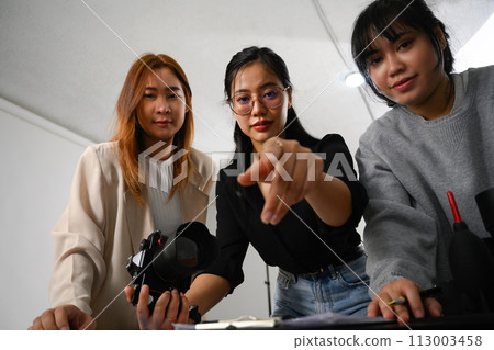 Group of young creative people working together in studio during photo session 113003458