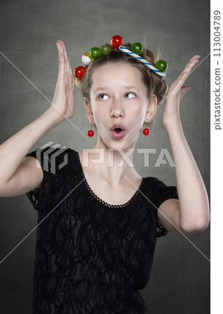 Funny teen girl with a wreath of sweets on her head fooling around in front of the camera. 113004789