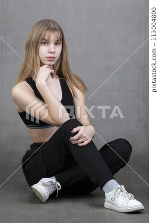 Plain teenage girl in sportswear on a gray background. 113004800