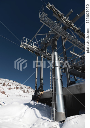 A cable car station high in the mountains under construction. Snowy mountain landscape and construction of a metal structure for a cable car A cable car station high in the mountains under construction. Snowy mountain landscape and construction of a metal structure for a cable car 113005050