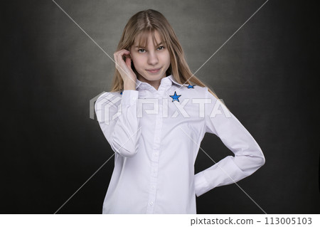 Happy teenage girl in a white shirt is shot against a gray background. 113005103