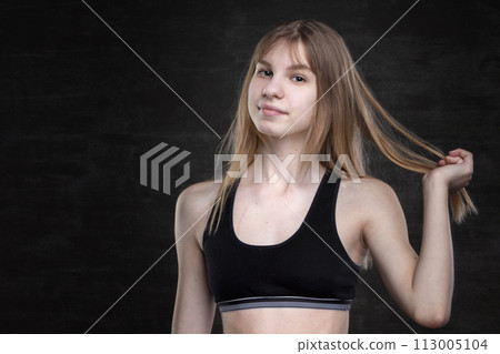 Teenage girl in a sports shirt on a dark background. Teenage girl in a sports shirt on a dark background. 113005104