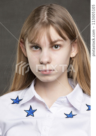 Portrait of a teenage girl in a white shirt and black hat is shot against a gray background. Portrait of a teenage girl in a white shirt and black hat is shot against a gray background. 113005105