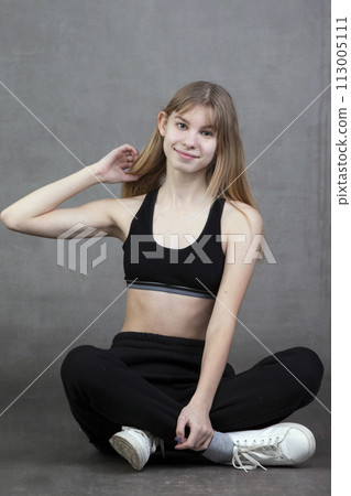 Plain teenage girl in sportswear on a gray background. Plain teenage girl in sportswear on a gray background. 113005111
