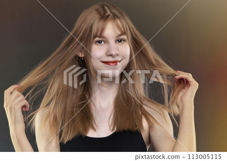 Beautiful teenage girl with long hair on and makeup on a dark background. Beautiful teenage girl with long hair on and makeup on a dark background. 113005115