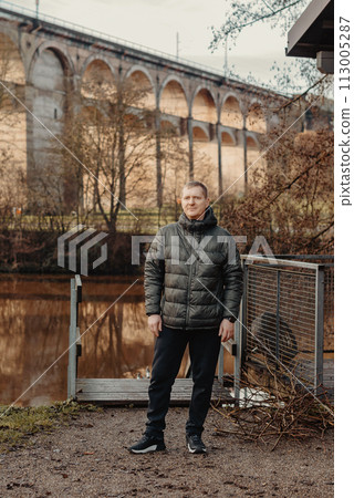 Timeless Elegance: 40-Year-Old Man in Stylish Jacket by Neckar River and Historic Bridge in Bietigheim-Bissingen, Germany Timeless Elegance: 40-Year-Old Man in Stylish Jacket by Neckar River and Historic Bridge in Bietigheim-Bissingen, Germany 113005287