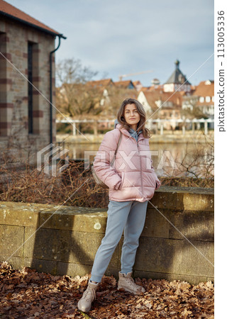 Young beautiful pretty tourist girl in warm hat and coat with backpack walking at cold autumn in Europe city enjoying her travel in Bietigheim-Bissingen, Deutschland. Outdoor portrait of young tourist 113005336