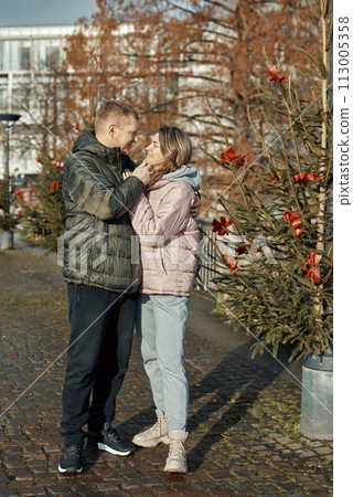 couple in love A guy and a girl hugging on the street of the old European town of Bietigheim-Bissingen in Germany on Christmas Eve. The city streets are decorated with Christmas trees and New Year's couple in love A guy and a girl hugging on the street of the old European town of Bietigheim-Bissingen in Germany on Christmas Eve. The city streets are decorated with Christmas trees and New Year's 113005358