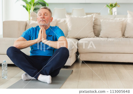 Yoga mindfulness meditation. Senior adult mature man practicing yoga at home. Mid age old grandfather sitting in lotus pose on yoga mat meditating relaxing. Older man doing breathing practice 113005648