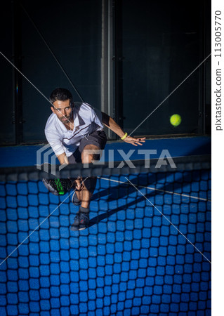 Man playing padel tennis indoor Man playing padel tennis indoor 113005770